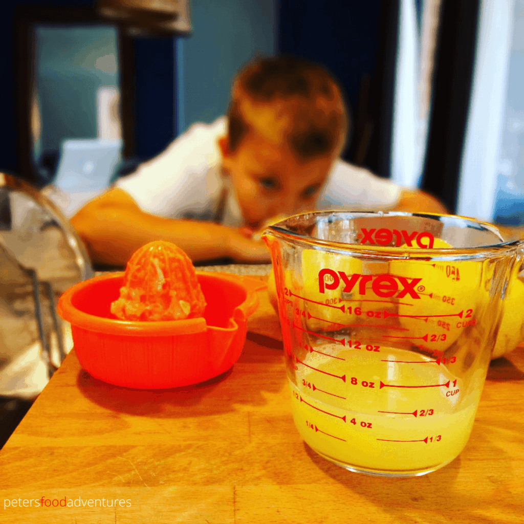 child measuring lemon juice in a glass jug