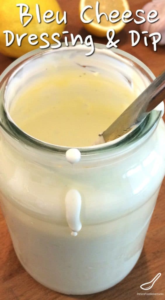 blue cheese dressing in a glass jar with cut lemons in the background