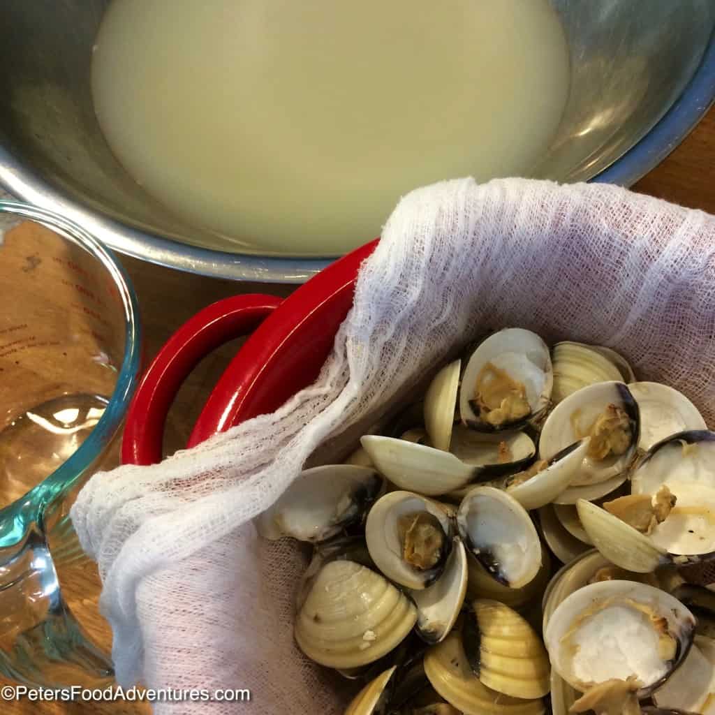 clam shells strained in a colander beside clam broth