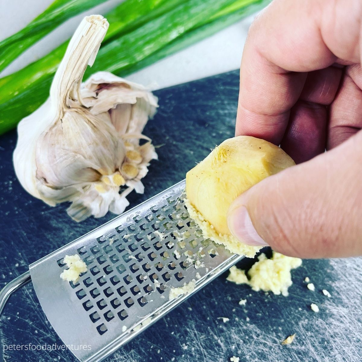 grating ginger on a grater with garlic