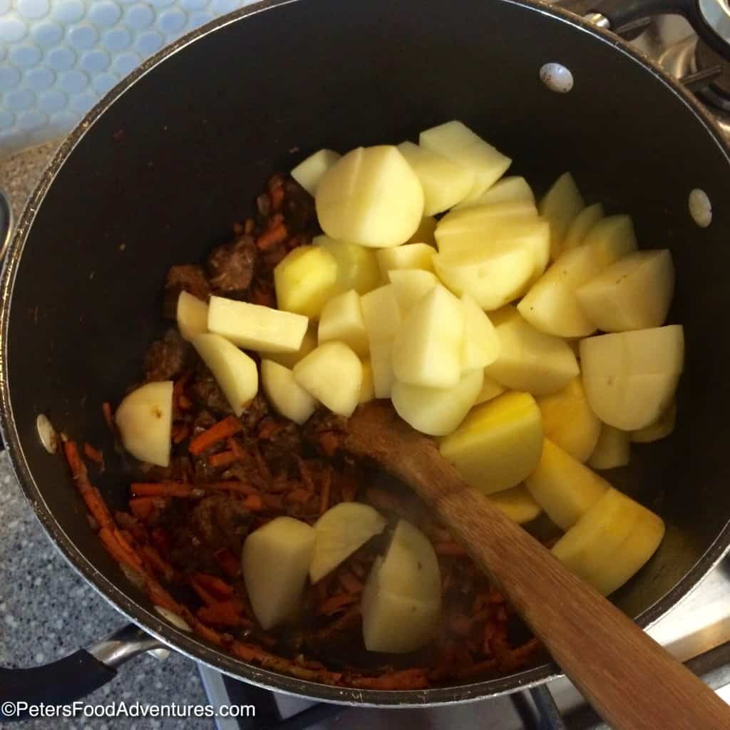 Making Kavardak in a pot with chopped potatoes