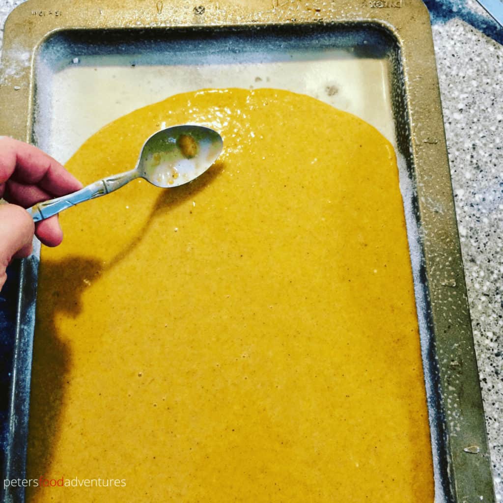spreading pumpkin roll batter with a spoon