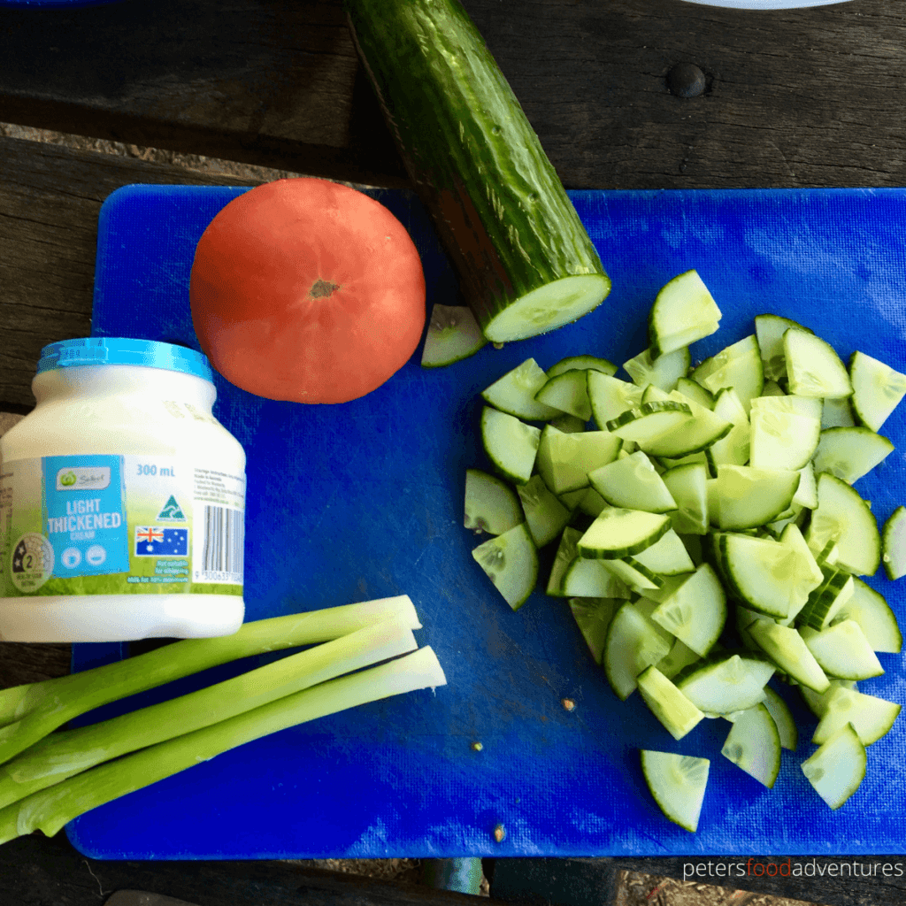 cucumber tomato salad ingredients on a blue cutting board
