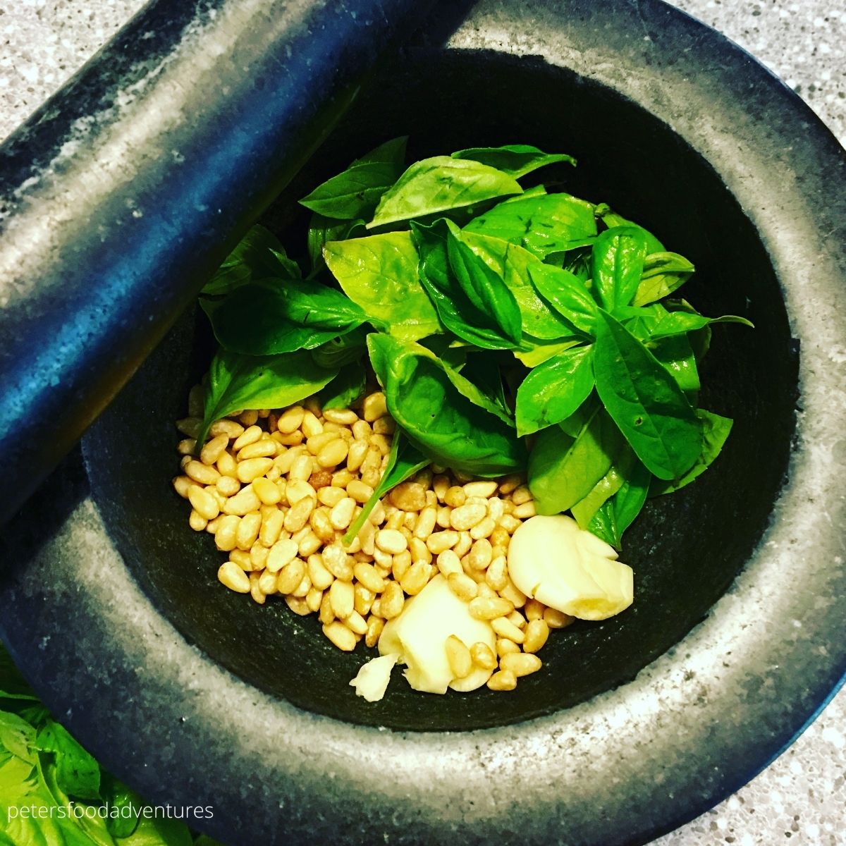 pesto ingredients placed in pestle and mortar