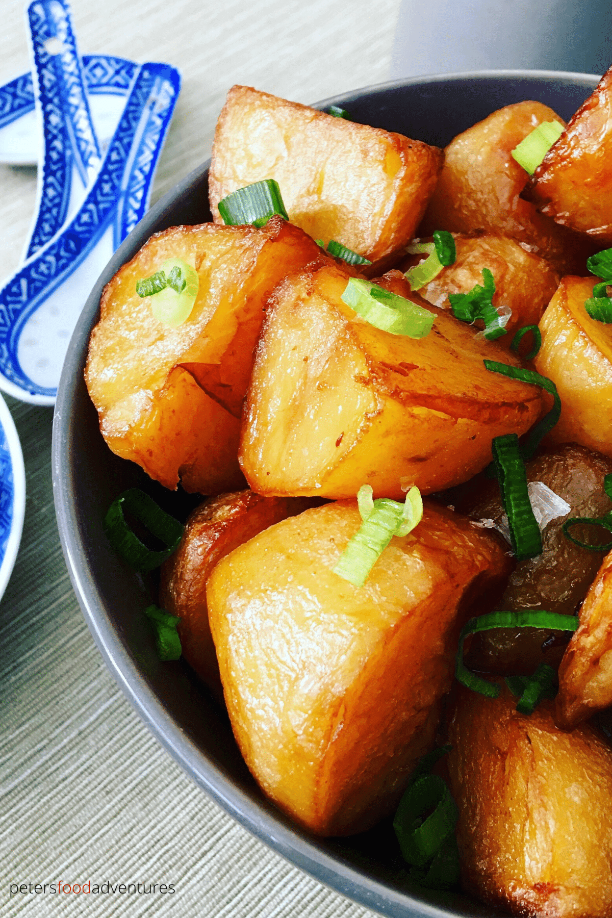 asian potatoes in a bowl beside chinese spoons