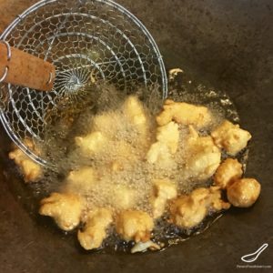 Frying battered chicken pieces in a wok