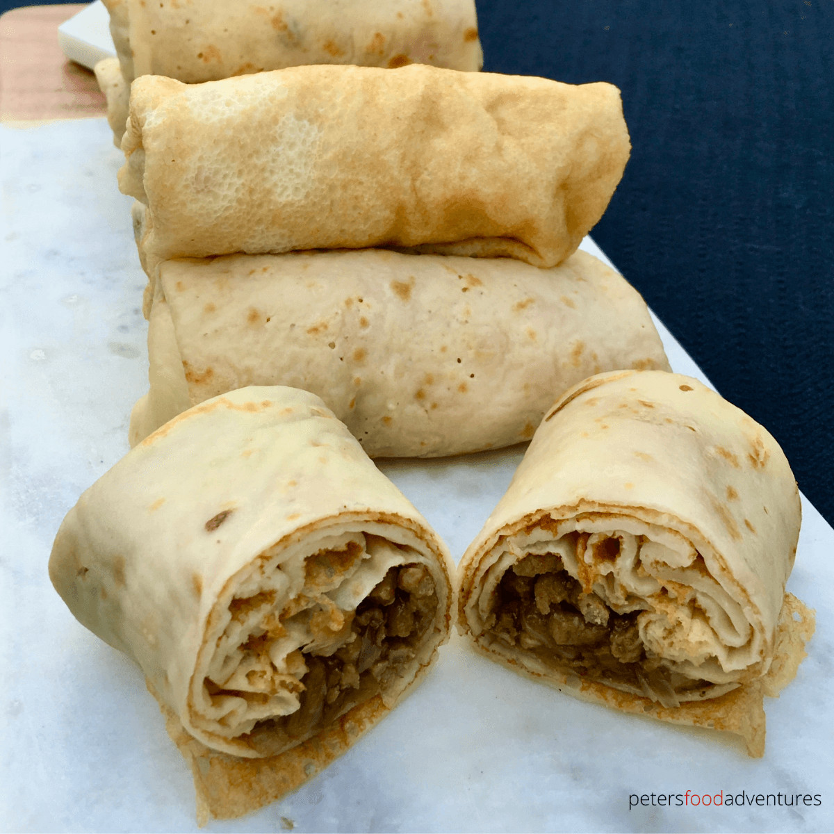 Russian Stuffed Blinchiki, also called Russian Crepes, are a thin rolled pancake stuffed full of savory meaty goodness. Not dry, fully of flavor and juicy. Meat Blini (Блинчики с мясом)