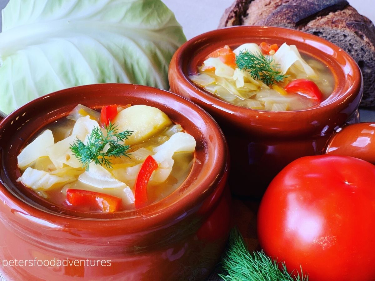 2 bowl of cabbage soup beside a cabbage and tomato