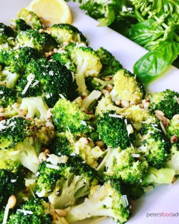 garlic roasted broccoli on a plate with pine nuts