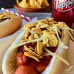 hot dog topped with chili, doritos, cheese and jalapeños