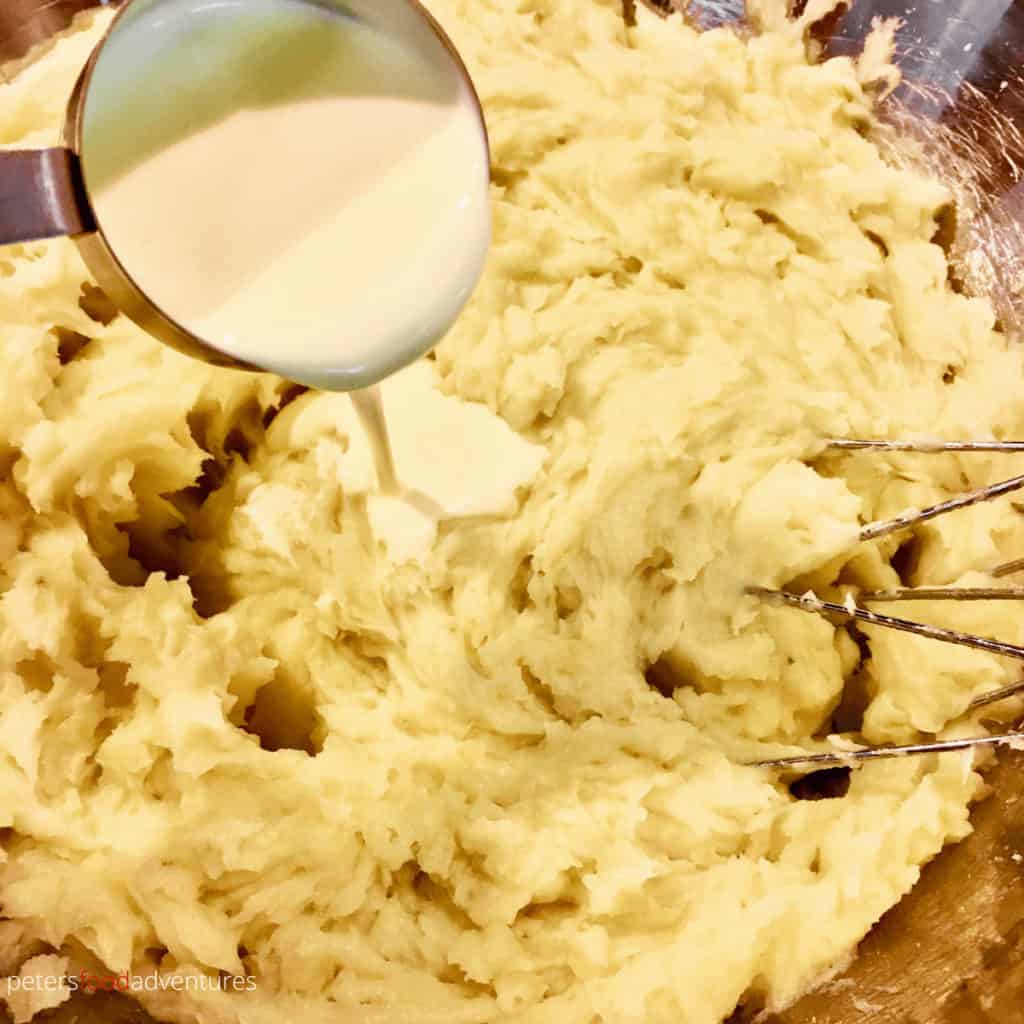 making creamy mashed potatoes, pouring whipping cream over potatoes