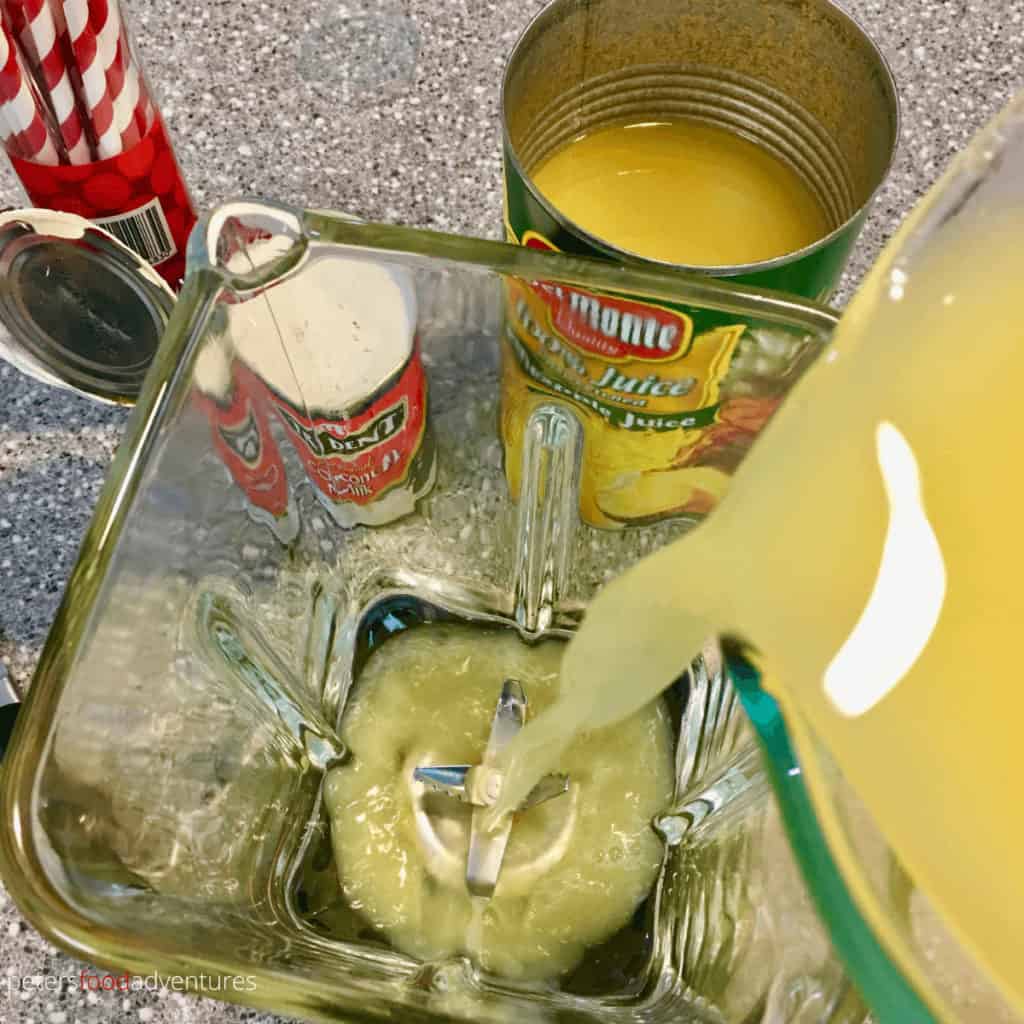 pouring pineapple juice into a blender to make pina coladas