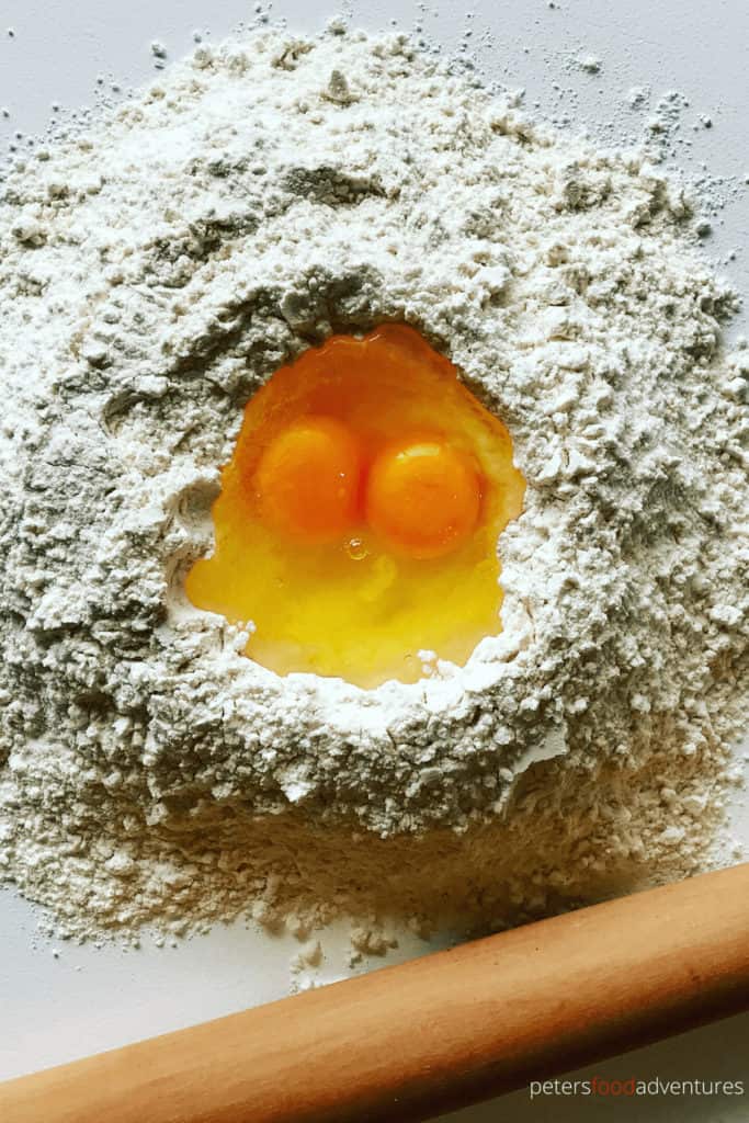 making pierogi dough with eggs in a flour well