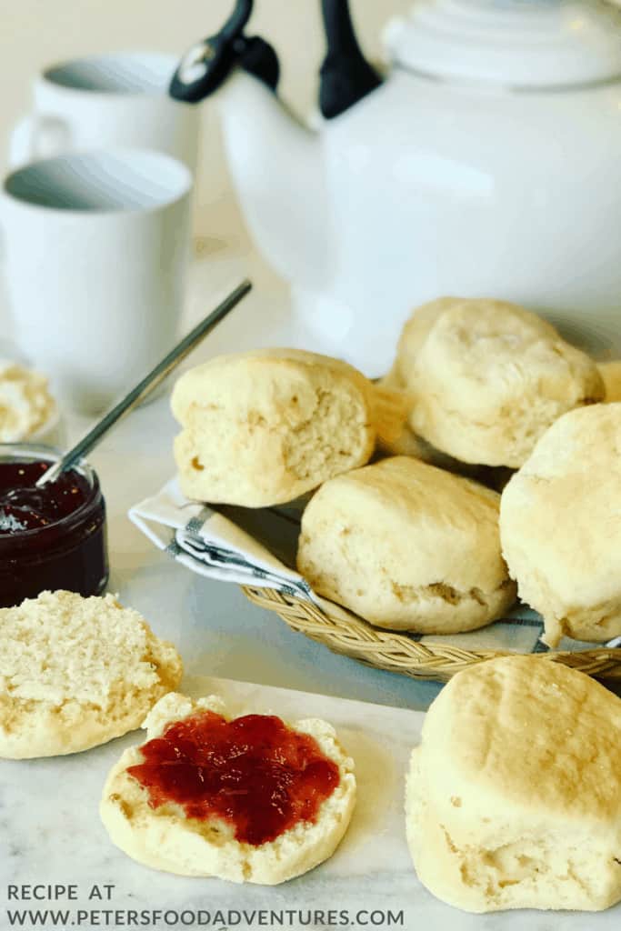 Scones in a basket on a breakfast table with tea cup and a kettle.