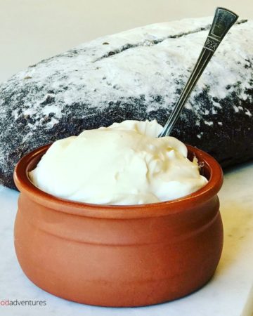 sour cream in a bowl with a loaf of bread