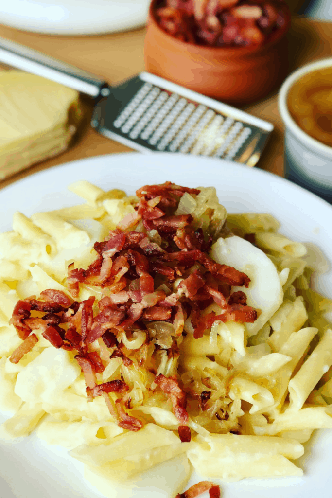 Alplermagronen - Swiss Mac and Cheese is the ultimate Alpine comfort food. Macaroni, Swiss cheese, potatoes, caramelized onions, and bacon, served with apple sauce. Your family will love this dinner recipe! Swiss Mac and Cheese with Potatoes (Älplermagronen)