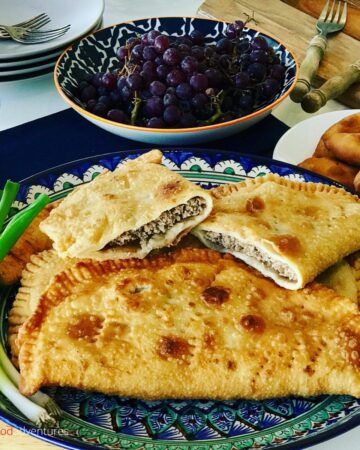 chebureki on a plate, with filling exposed