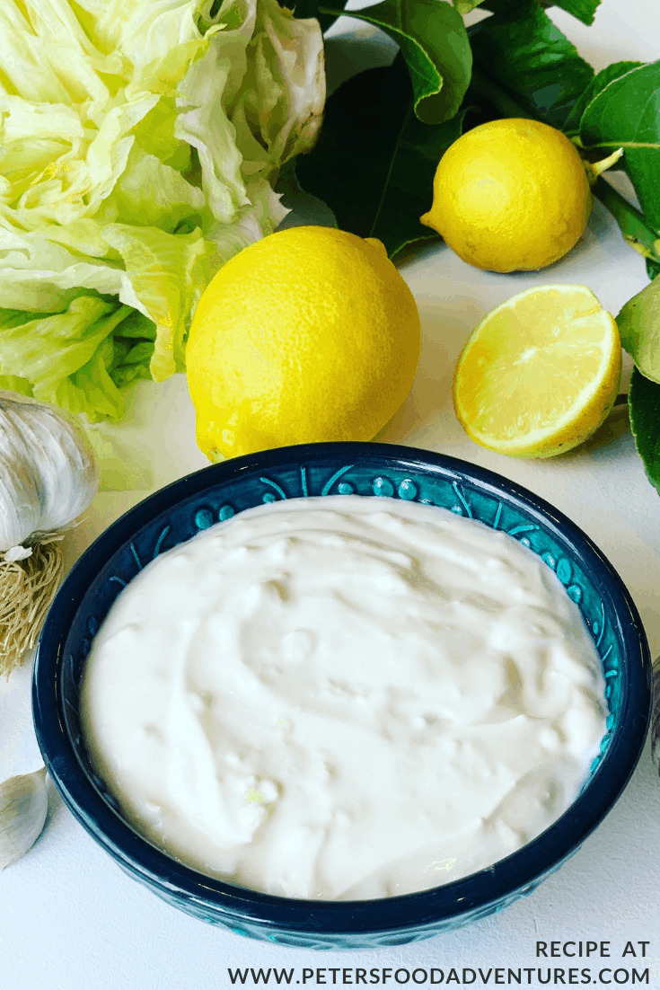 Yogurt Garlic Sauce in a bowl with fresh lemons