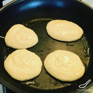 4 pancakes frying on a skillet