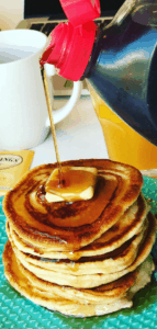 Syrup being poured over an pancake stack