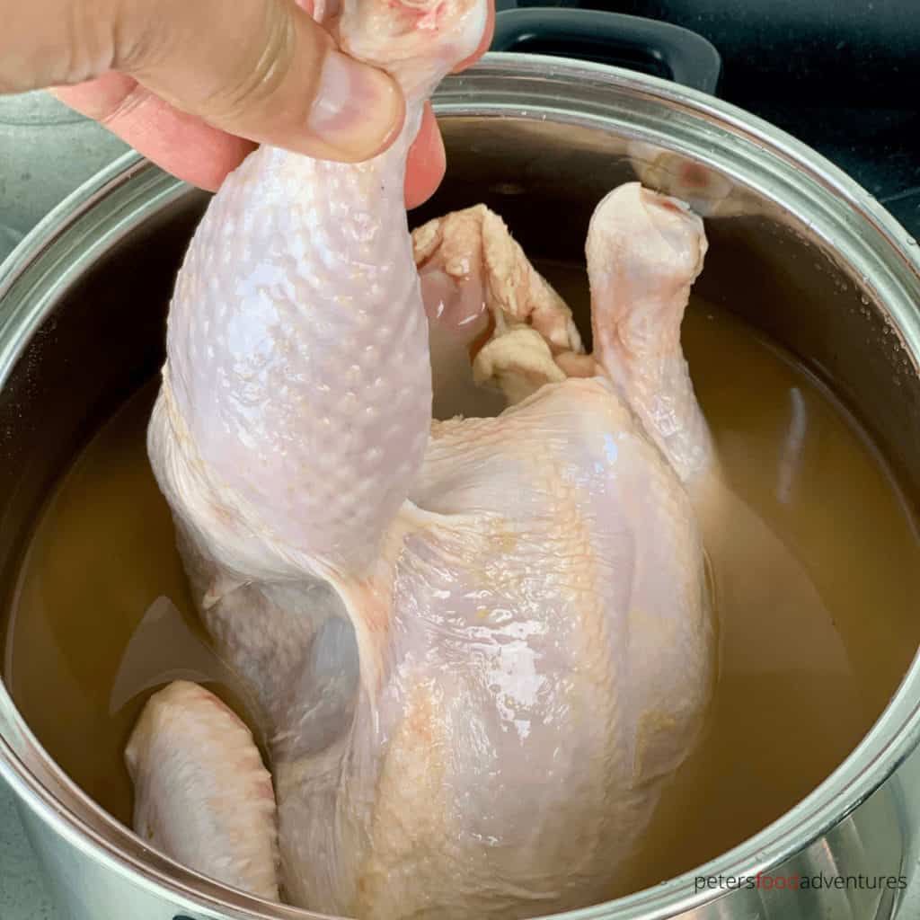 lowering a raw chicken into brine