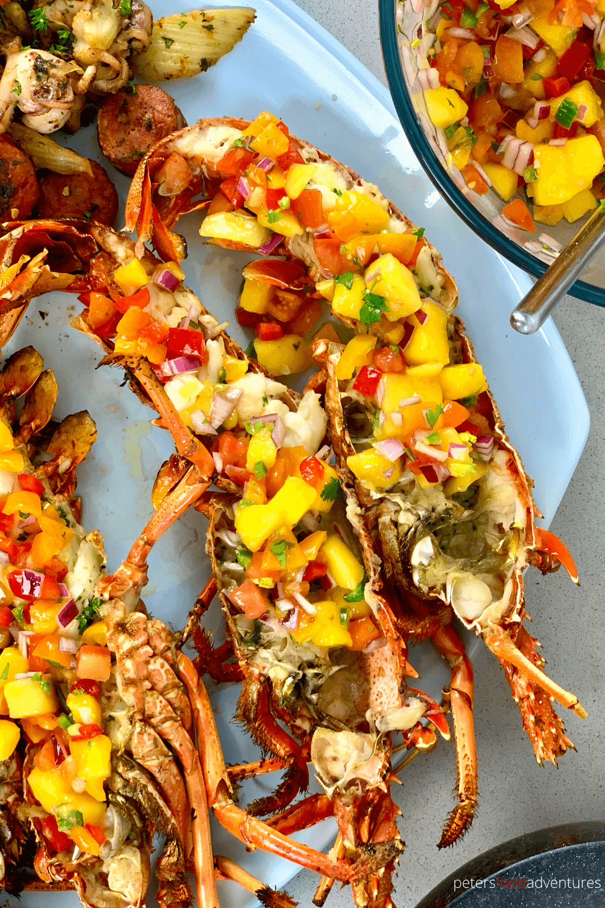 plate of grilled lobsters, cut in half and topped with mango salsa