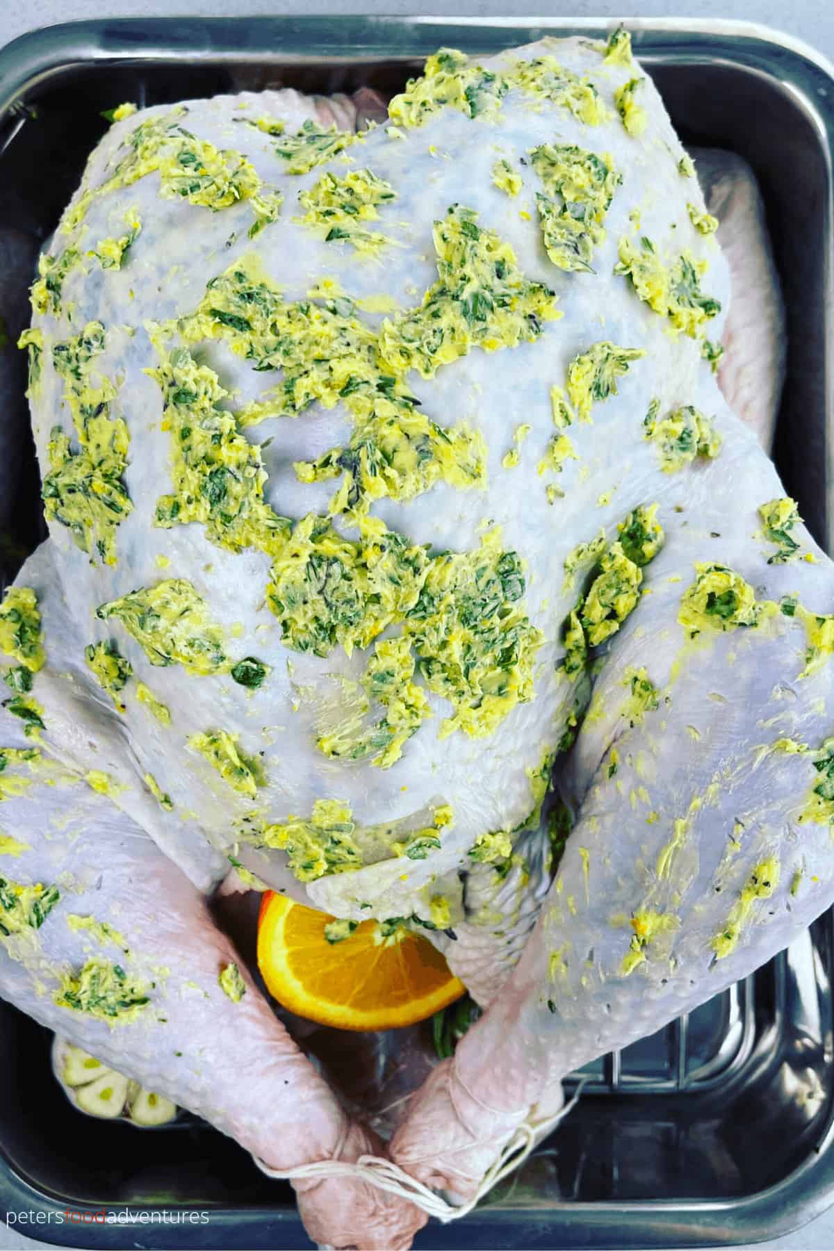 herb butter covering a turkey before placing in the oven