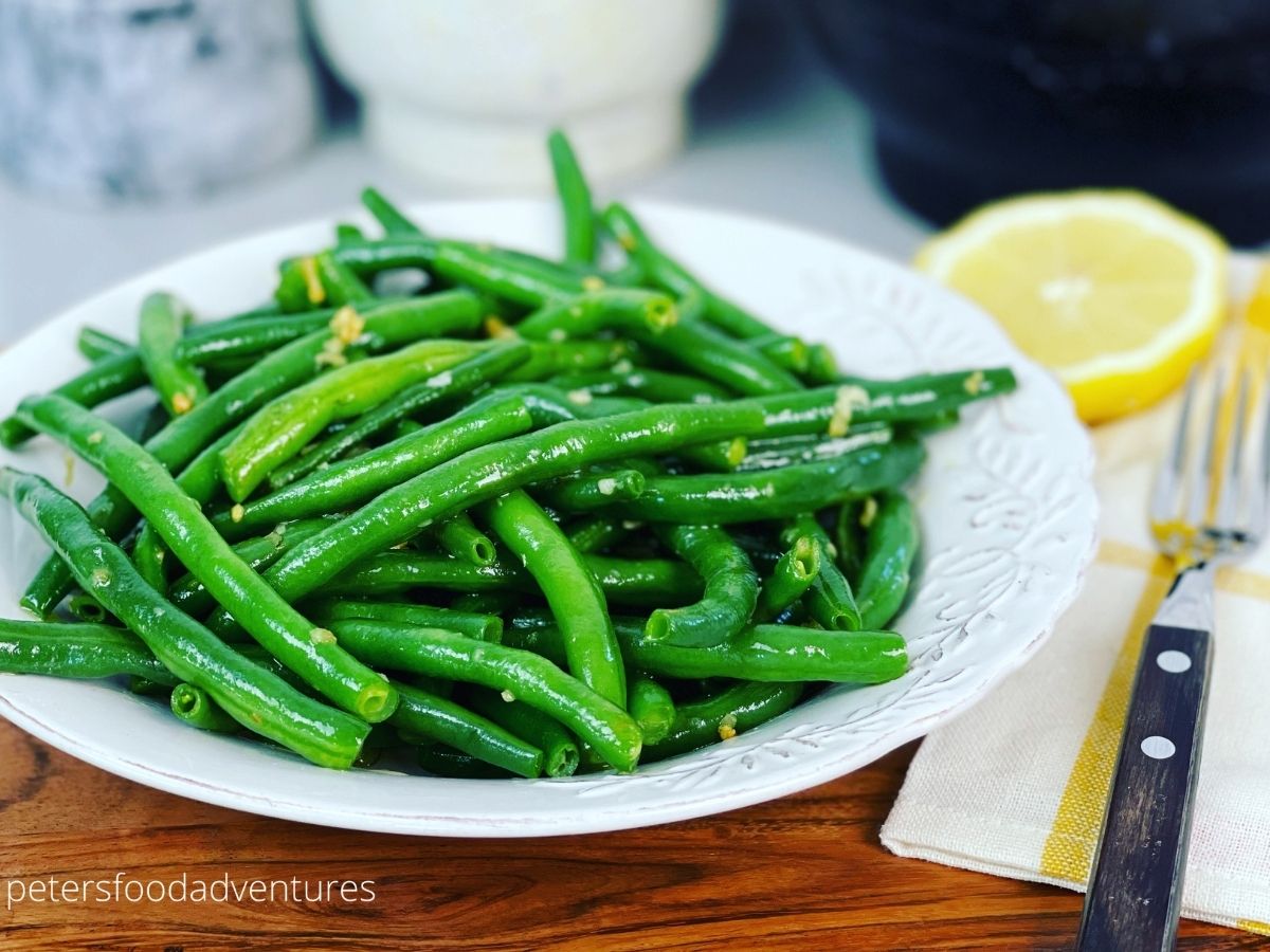garlic green beans in a bowl with lemon wedge