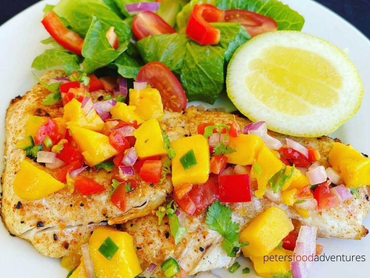 grilled snapper on a plate topped with mango salsa