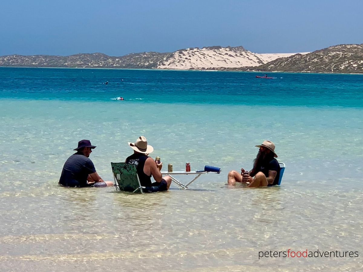 3 men sitting in the water at coral bay